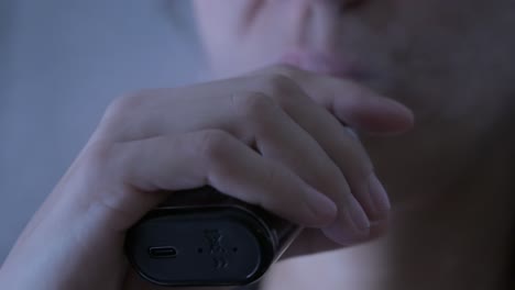 primer plano de una mujer fumando un cigarrillo electrónico y soplando humo