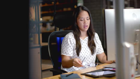 Biracial-woman-stretches-at-her-business-desk-in-the-office