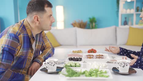 restless and angry man fighting and shouting with his wife while having breakfast.