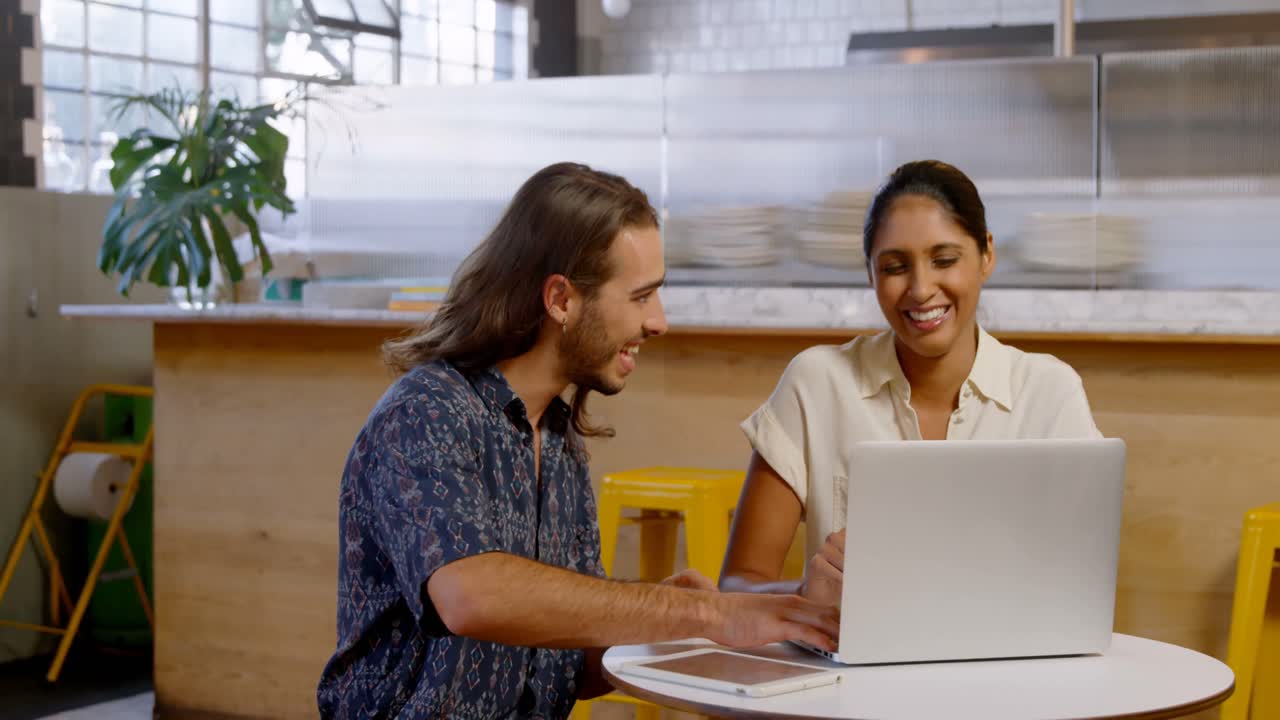 Colegas conversando frente a un portátil en la cafetería 4k