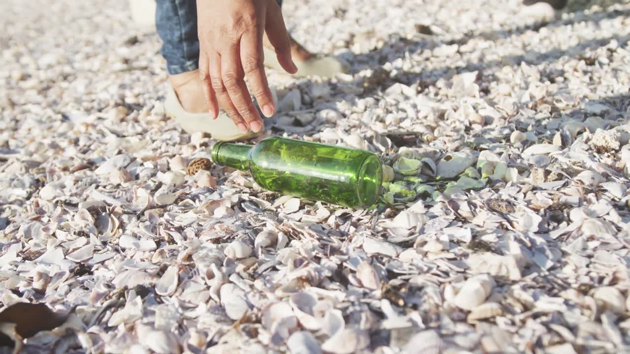 sección baja de una pareja afroamericana de alto nivel limpiando la playa, cámara lenta