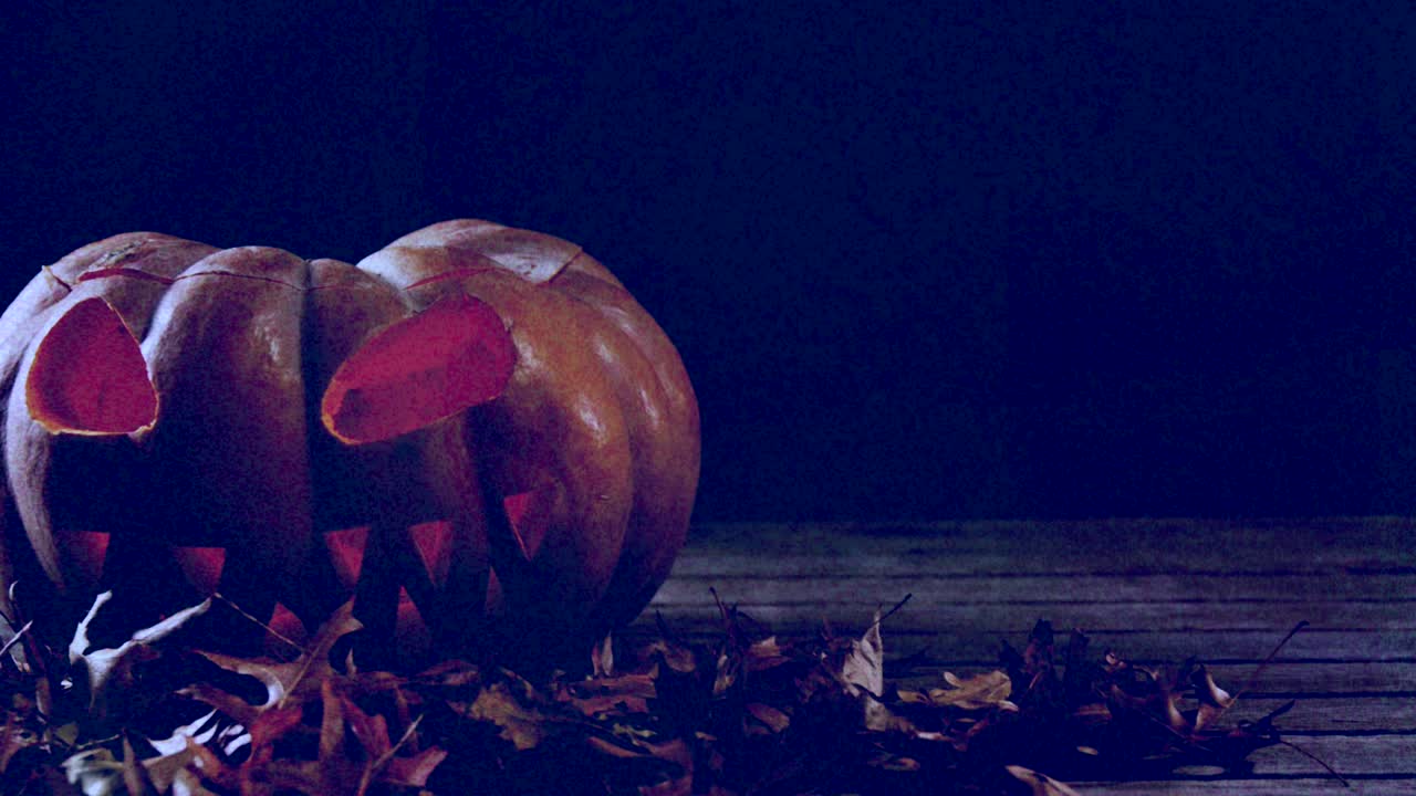 calabaza y hojas aterradoras en la superficie de madera contra un fondo parpadeante