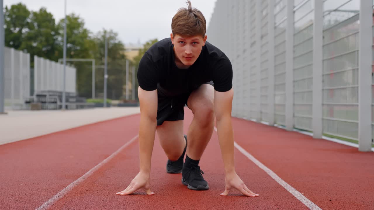 Young runner in position for a sprint workout on a professional all-weather track