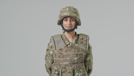retrato de estudio de una joven soldado en uniforme militar contra un fondo plano