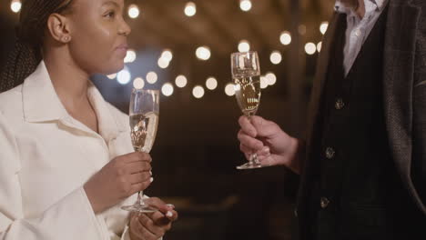 Man-And-Woman-Holding-Champagne-Glasses-And-Talking-To-Each-Other-At-New-Year's-Eve-Party-2