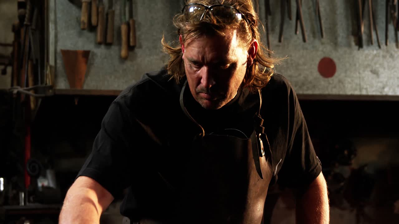 кузнец, работающий на железном стержне