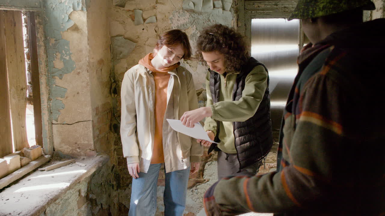производственный рабочий помогает своей коллеге-женщине читать сценарий в разрушенном здании