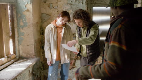 a production worker helping his female coworker read a script in a ruined building