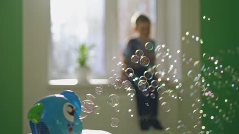 colorful circle bubbles flying in the room on the blur background with a boy. special device for creating soap bubbles on the table. soap bubbles show inside the room.