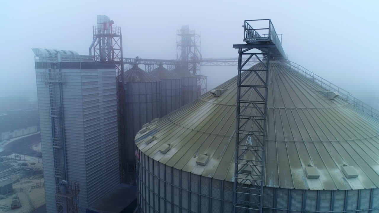Metal tanks and constructions at modern grain processing plant. Foggy winter weather backdrop. Aerial view.