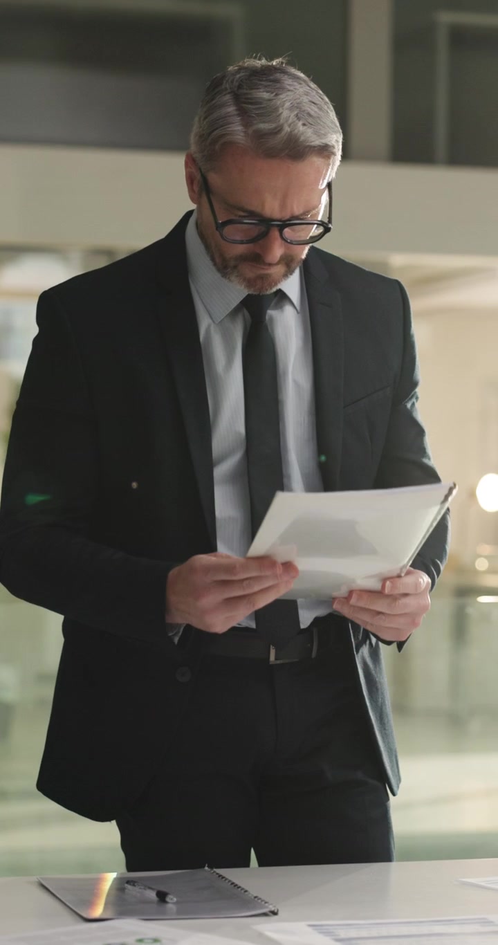 Uomo d'affari maturo che esamina documenti in un ufficio moderno