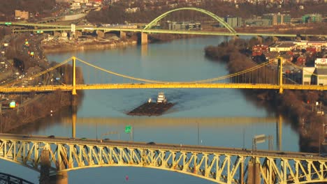 barges travel under the bridges of pittsburgh pa