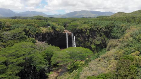 version one. aerial reveal of wailua falls, over trees in wailua state park in kauai, hawaii.