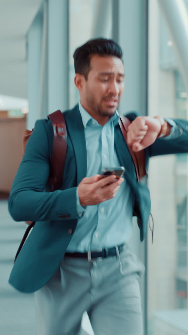 Empresario estresado corriendo y revisando su teléfono en el pasillo del aeropuerto