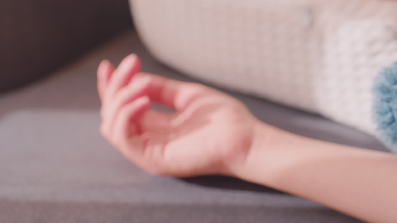 Close up blur view of woman napping on bed with blue blanket, arm resting comfortably while head lies on pillow, calm and peaceful indoor moment showing relaxation