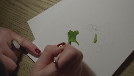 A-close-up-shot-of-female-hands-painting-holly-leaves-on-a-Christmas-card