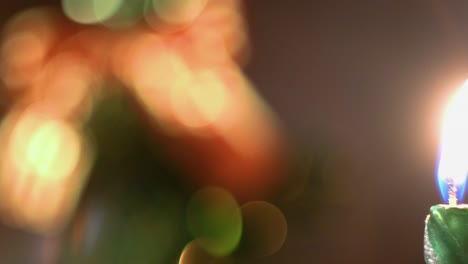Burning Green Candle Against Blurred Christmas Tree