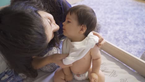 la madre está vistiendo a su bebé.