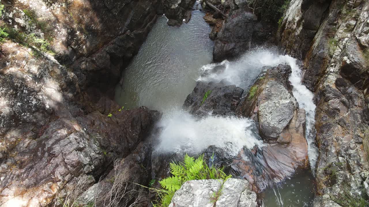 cascadas gemelas que caen en cascada sobre una pared de roca erosionada en un importante y aislado pozo de natación indígena