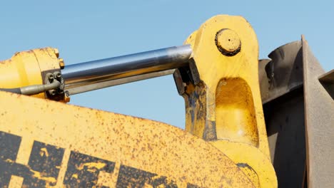 hydraulic arm of digger moving bucket loader while working on construction site, close up