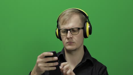 Guy-listens-to-music-in-wireless-yellow-headphones-and-dances.-Chroma-key