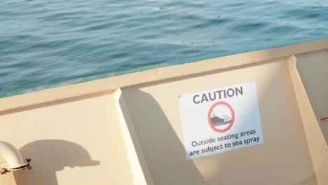 caution, outside seating areas are subject to sea spray posted on sailing boat in sydney harbour, nsw, australia