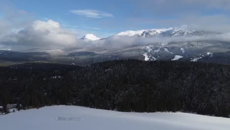 Frozen-Lake-With-Surrounding-Pine-Forest-And-Snow-covered-Mountain-Range-During-Winter-In-Whistler,-Canada