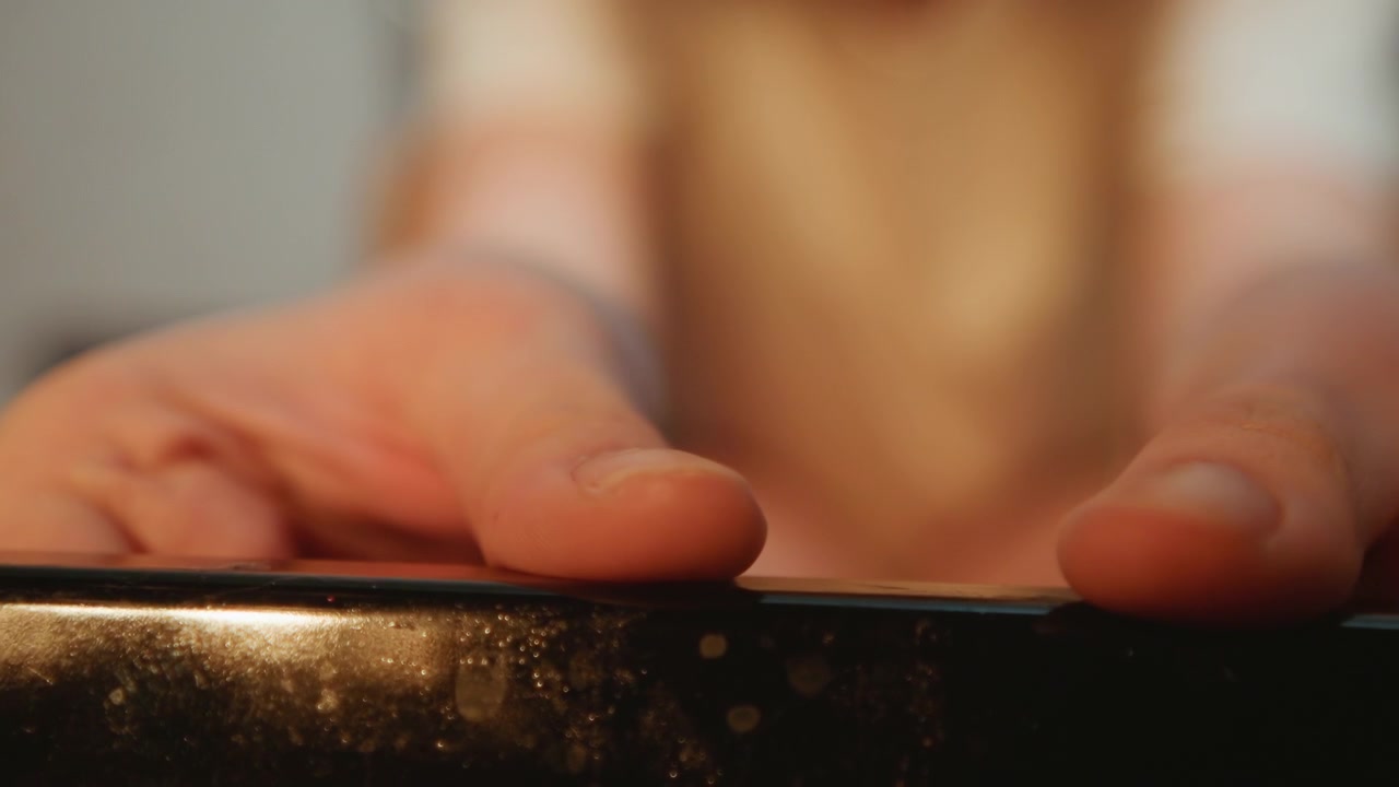 Lowangle oven front with hands white cook reaching during cooking. Close focus on fingertips on speckled edge, blurred legs in background. Warm domestic light, tactile moment of retrieval as baker