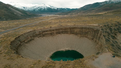 Cautivador-Retiro-Aéreo,-Develando-El-Místico-Pozo-De-Las-Ánimas-En-Medio-De-Montañas-Nevadas