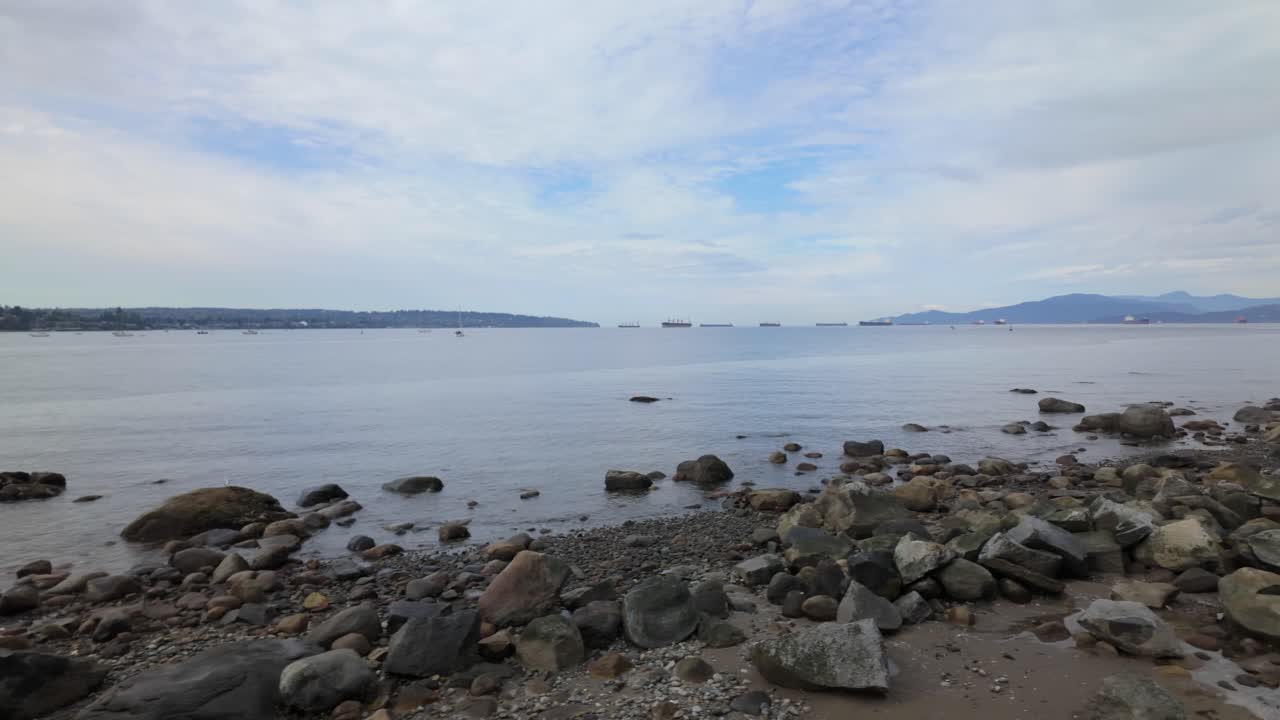 Gimbal wide dolly shot of the rocky shoreline along English Bay in Vancouver, British Columbia, Canada. 4K at 30 FPS