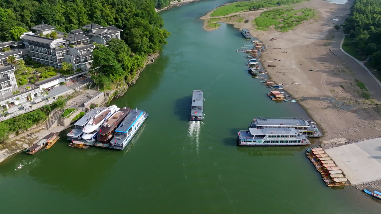 Drone tilting toward a Li river cruise ship in front of the Yangshuo town, China