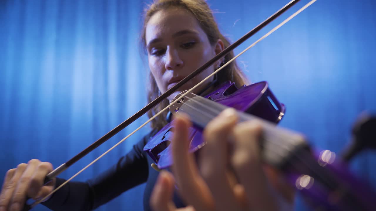 un primer plano de una mujer músico tocando el violín en el escenario, componiendo, haciendo música.