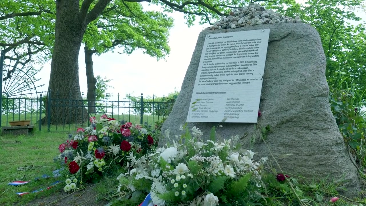 Pietra commemorativa e omaggi floreali in un ambiente rurale pacifico