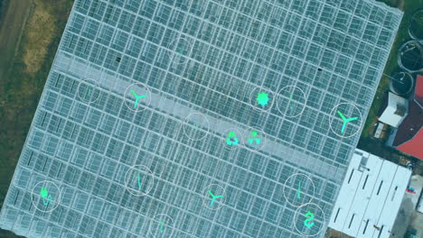 digital icons overlaying agricultural technology concepts in aerial view of greenhouse