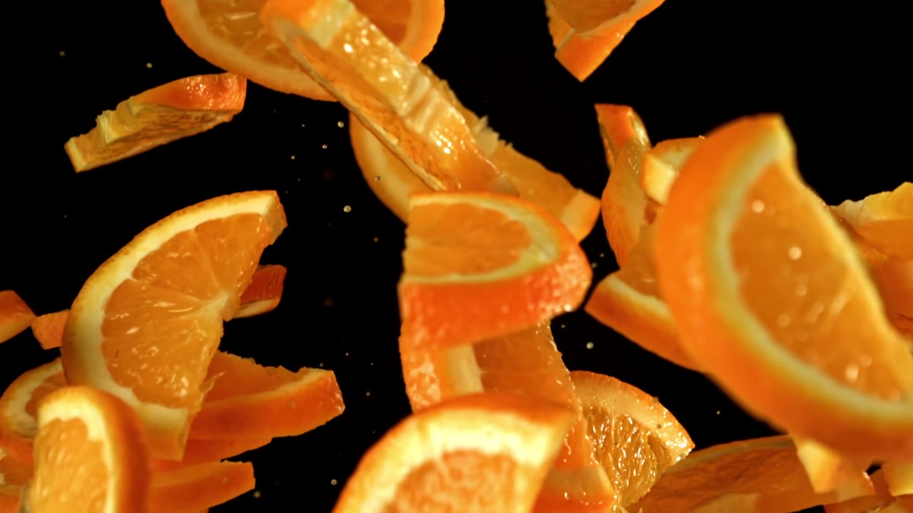 Fatias de Laranja Caindo em Câmera Lenta em Fundo Preto