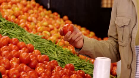 hombre seleccionando tomates en la sección orgánica