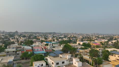 Aerial-forward-shot-of-Shaheed-e-Millat-Road-surrounded-by-crowded-city-in-Karachi,Pakistan