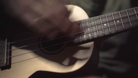 close up of a man's hands strumming a ukulele