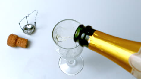 Champagne-being-poured-into-flute-on-white-surface