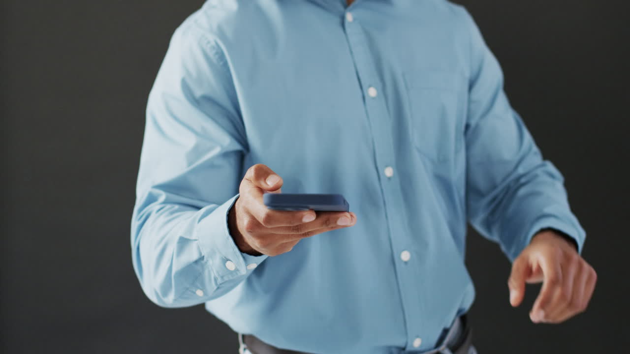 video de un hombre de negocios biracial con un teléfono inteligente y usando una pantalla holográfica, espacio de copia