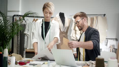 woman tailor with colleage man choosing clothes pieces