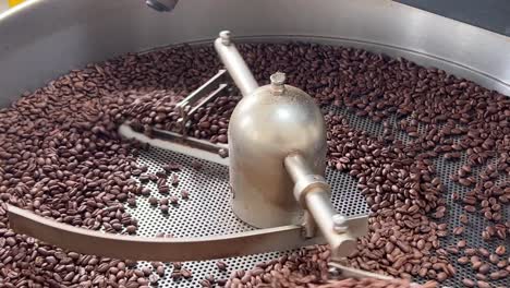 granos de café especiales girando en la bandeja de enfriamiento y mezcla para reducir el calor de manera uniforme después del tostado, toma de fábrica del almacén de producción de la industria de alimentos y bebidas, toma de primer plano extremo