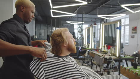 barber putting haircutting cape on client