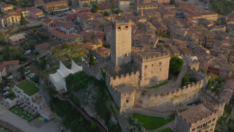 slow aerial, reveal shot of the castello scaligero castle located near lake garda, italy