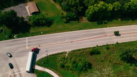 two red semi trucks and trailers taking right on a red light stop