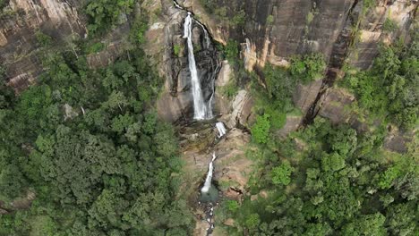 toma aérea en cámara lenta de una impresionante cascada que sale del agujero de la montaña rocosa, sri lanka