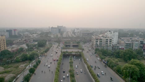 Aerial-Flyover-Of-Cars-And-Motorcycles-Driving-Through-Kalma-Chowk,-Pakistan