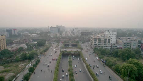 aerial flyover of cars and motorcycles driving through kalma chowk, pakistan