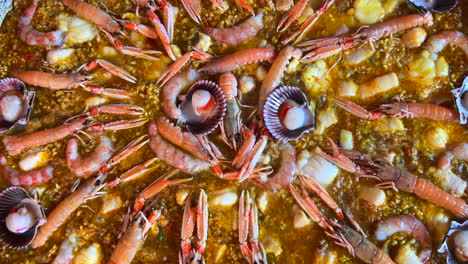 cooking a big traditional spanish seafood paella dish with shrimps, st jacques scallops and cigala norway lobsters nephrops norvegicus, tasty cooked rice with seafood, marbella spain, 4k shot