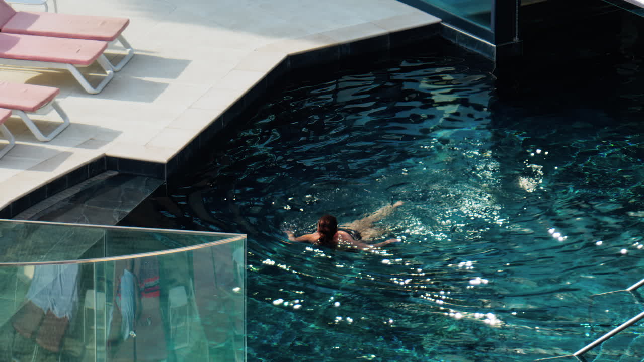 High angle view of a woman swimming in a pool on a sunny day